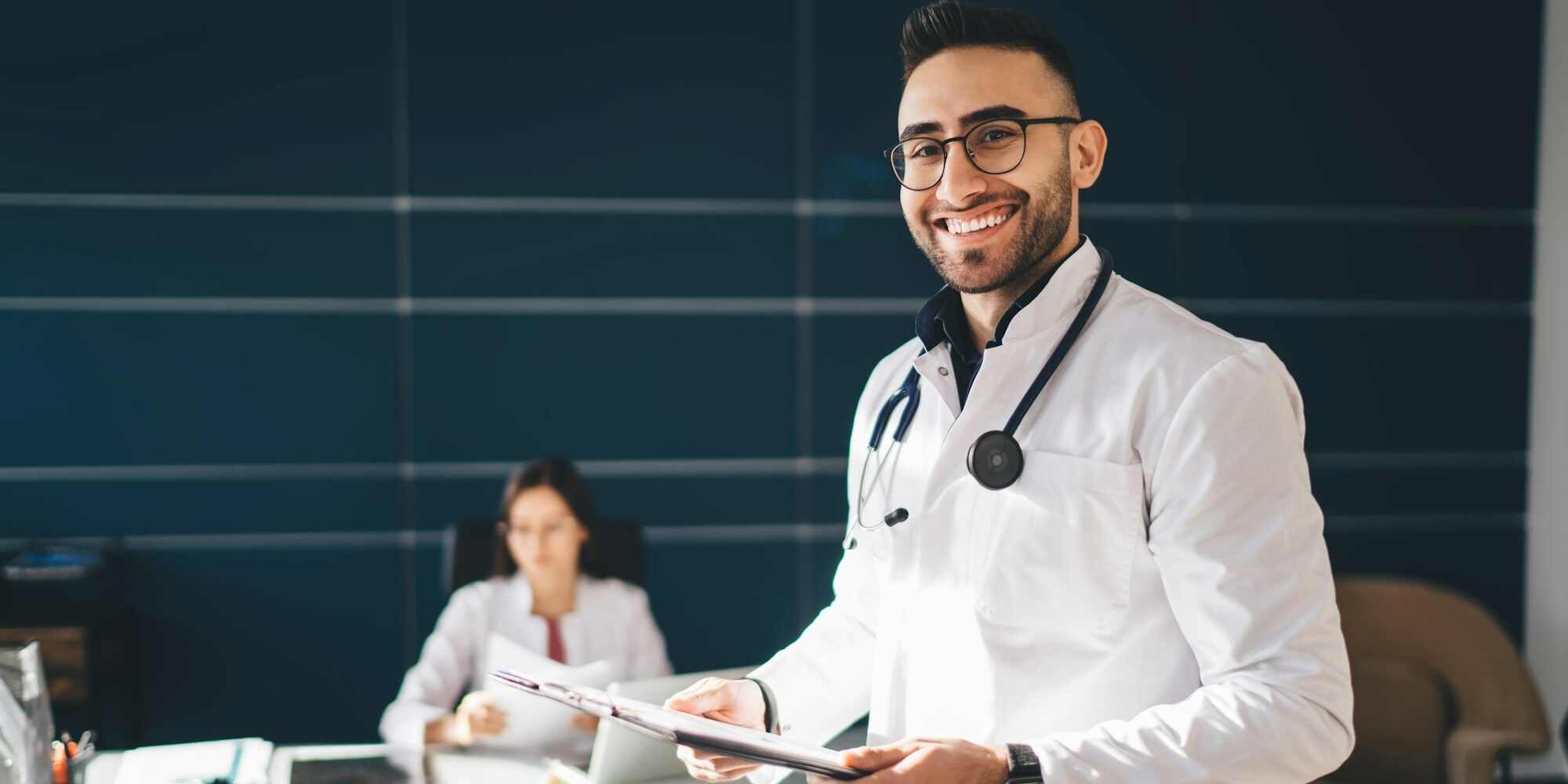 Cheerful male doctor in medical uniform working in hospital