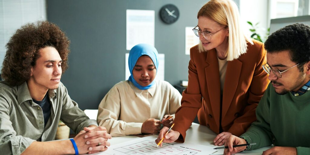 Confident teacher in eyeglasses explaining information in document