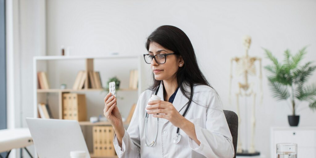 Doctor giving advice of pills during video call on laptop