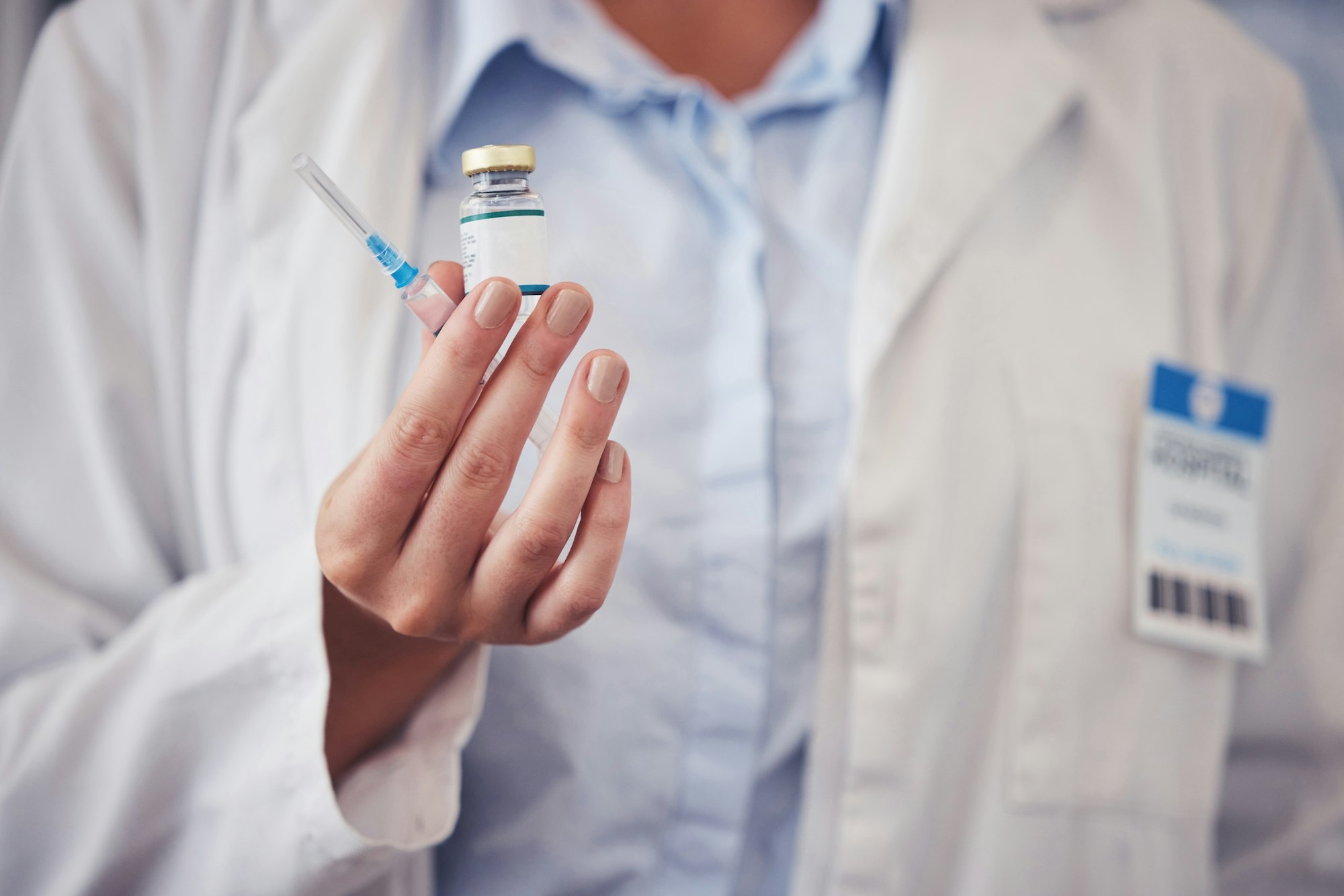 Doctor, hands and vaccine bottle with injection for medicine, safety and healthcare risk in clinic.