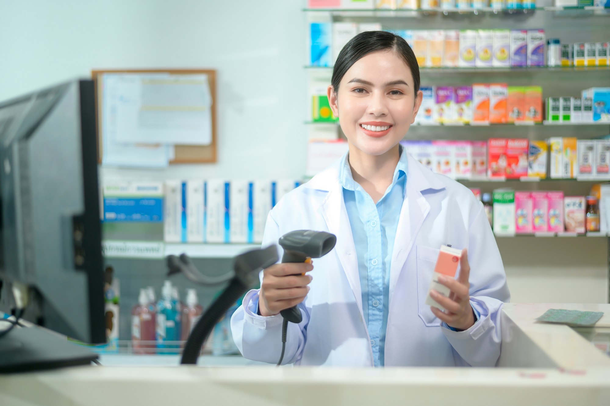 Female pharmacist scanning barcode on a medicine box in a modern pharmacy drugstore.