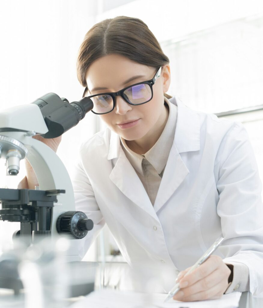 Brunette female scientific researcher making notes while studying coronavirus