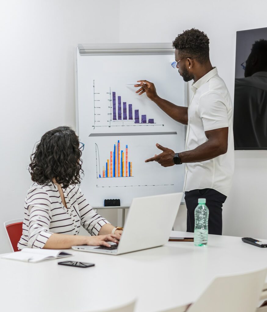 Business Professional Presenting Data Graphs To Coworker During Meeting