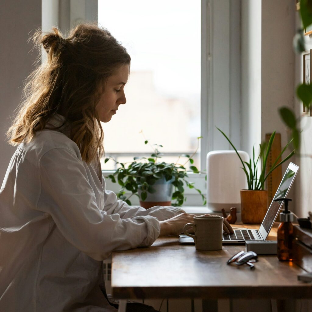 Woman freelancer remotely working on laptop from cozy home office, typing on keyboard. Distance job.