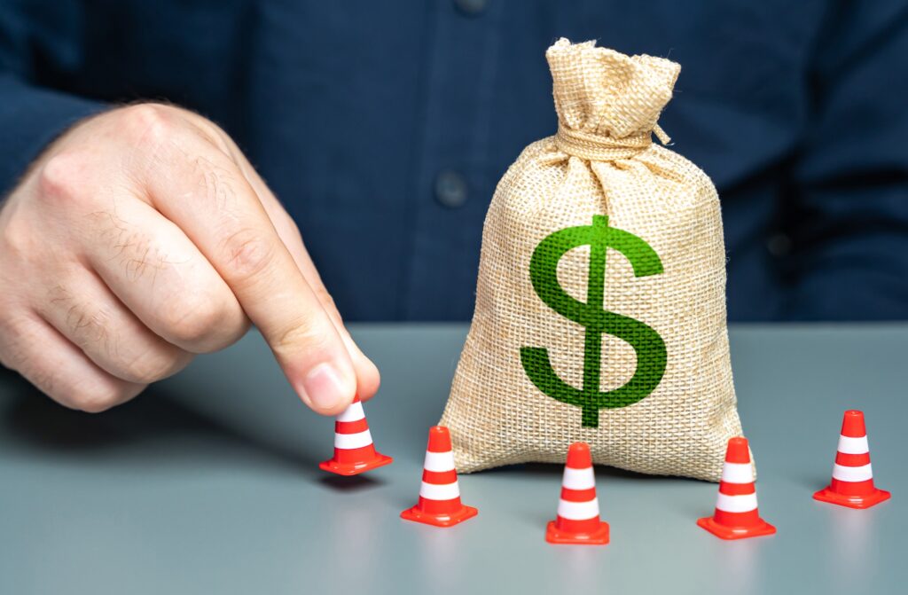 A man surrounds a dollar money bag with cones.