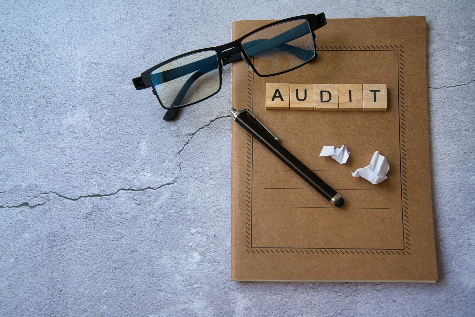 Process Auditing. Audit word written in wooden letters on a notepad, glasses, and a pen.