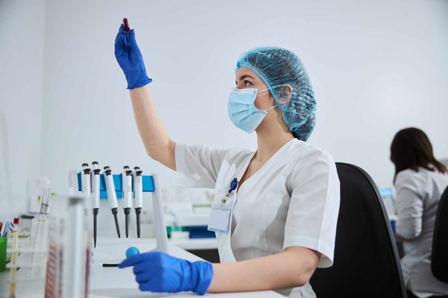 Lab technician in sterile latex gloves holding a vacutainer tube
