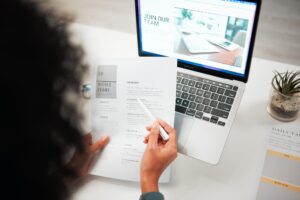 Hands, pen and human resources with CV, laptop with hiring news on company website and recruitment