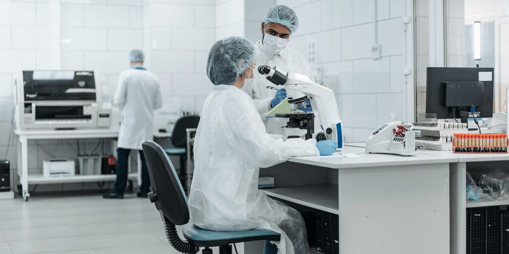 Professional standing inside a regulated pharmaceutical cleanroom, illustrating contamination control in drug manufacturing, GMP quality management system oversight, facility design and equipment qualification, and regulatory inspection readiness.